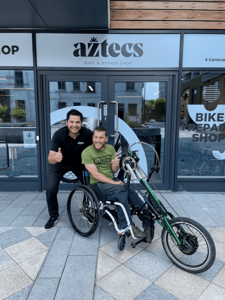 Marco and Ely with his assisted electric tricycle in front of Aztecs Bikes