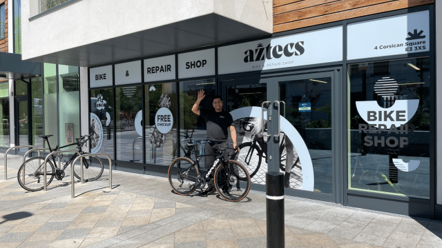 Marco owner of Aztecs Bikes waving at customer in front of the shop with a cervelo black bike